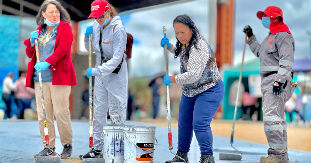 Foto de operarios en el Portal Américas pintando el piso 