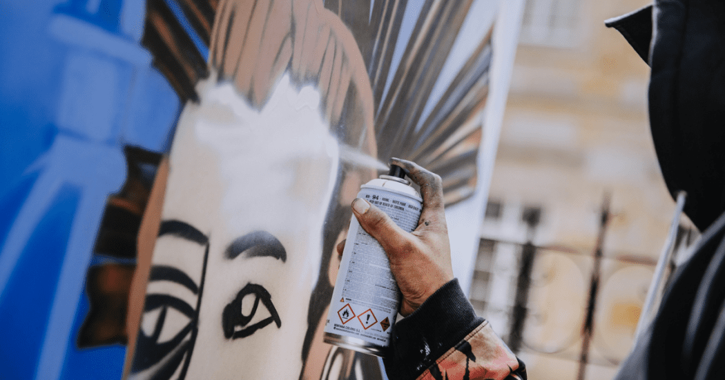 Fotografía de una persona grafiteando una pared