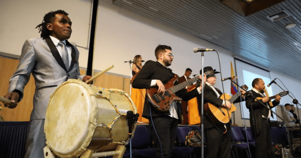 Imagen de una orquesta de personas con discapacidad tocando en tarima.