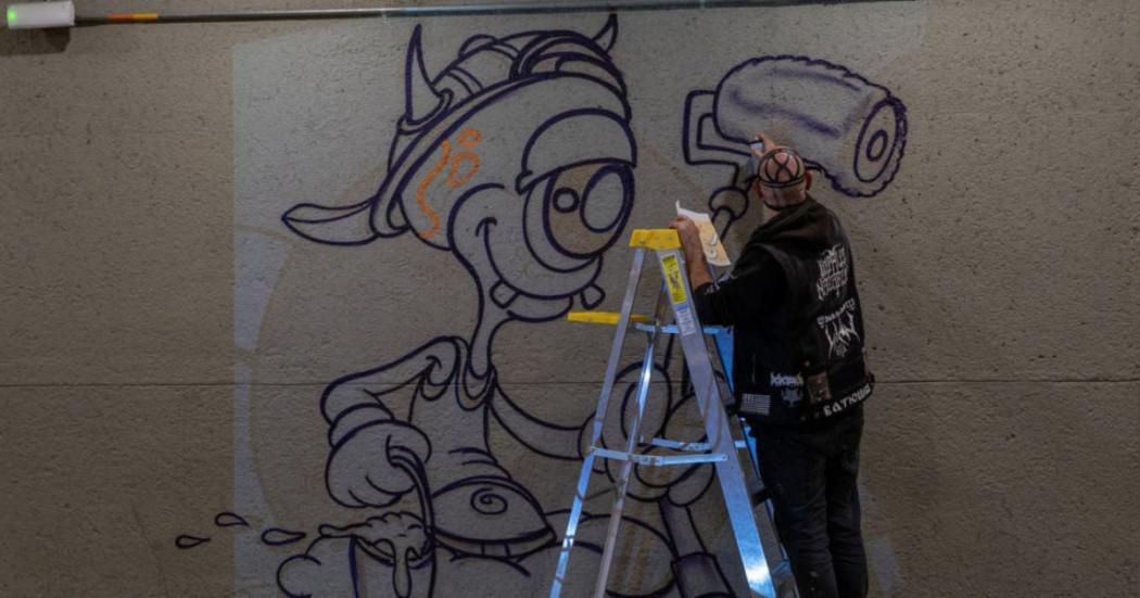 Foto que muestra un artista pintando una imagen en una pared