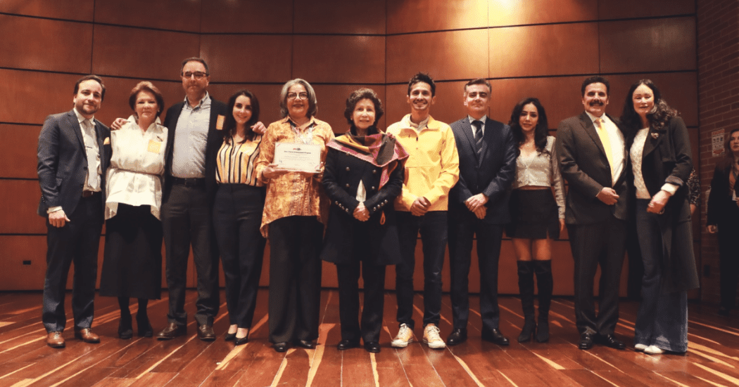 Foto de un grupo de profesionales en un auditorio, tras recibir un reconocimiento por su labor destacada en salud pública.