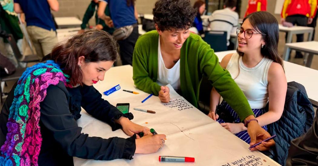 En la foto tres mujeres haciendo una cartelera para una presentación 