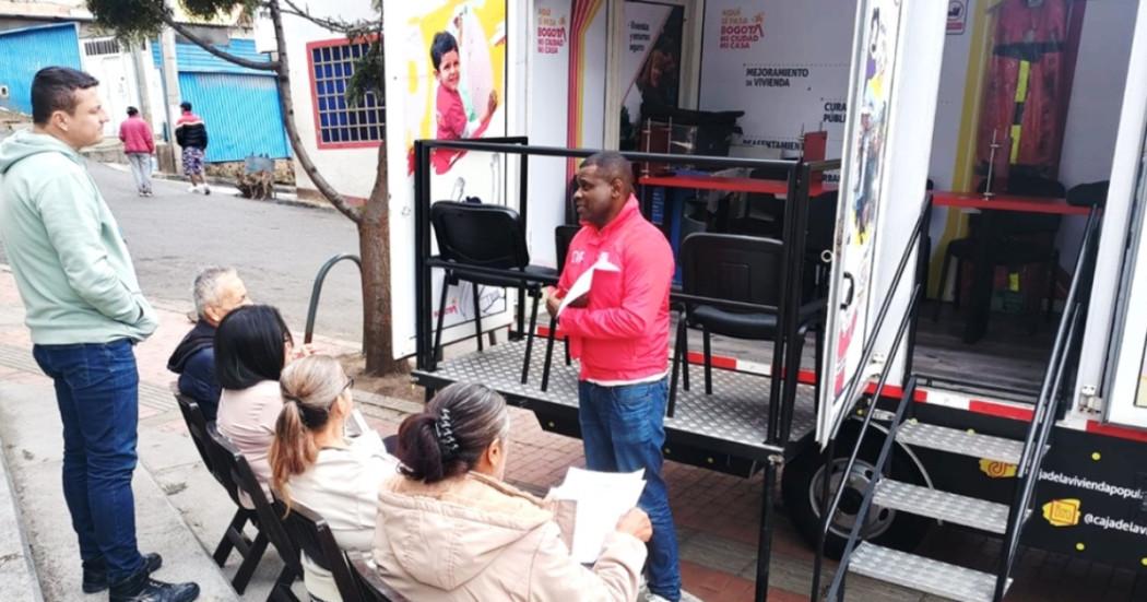 Foto que muestra la móvil de la Caja de Vivienda y personas hablando