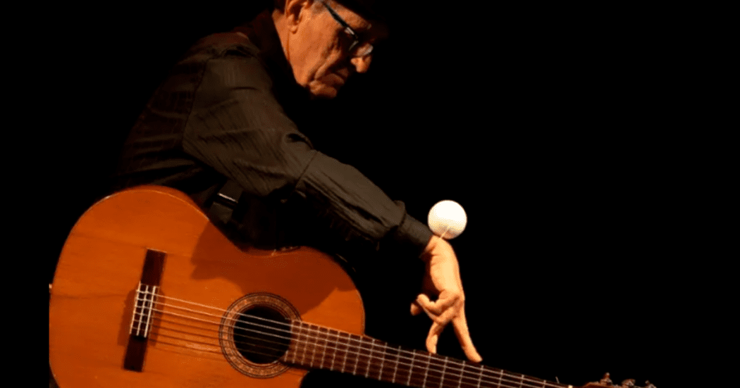 Imagen del titíritero sentado con una guitarra en sus piernas