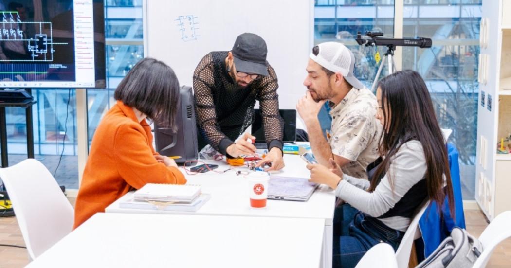 Foto con cuatro personas hablando al rededor de una mesa 