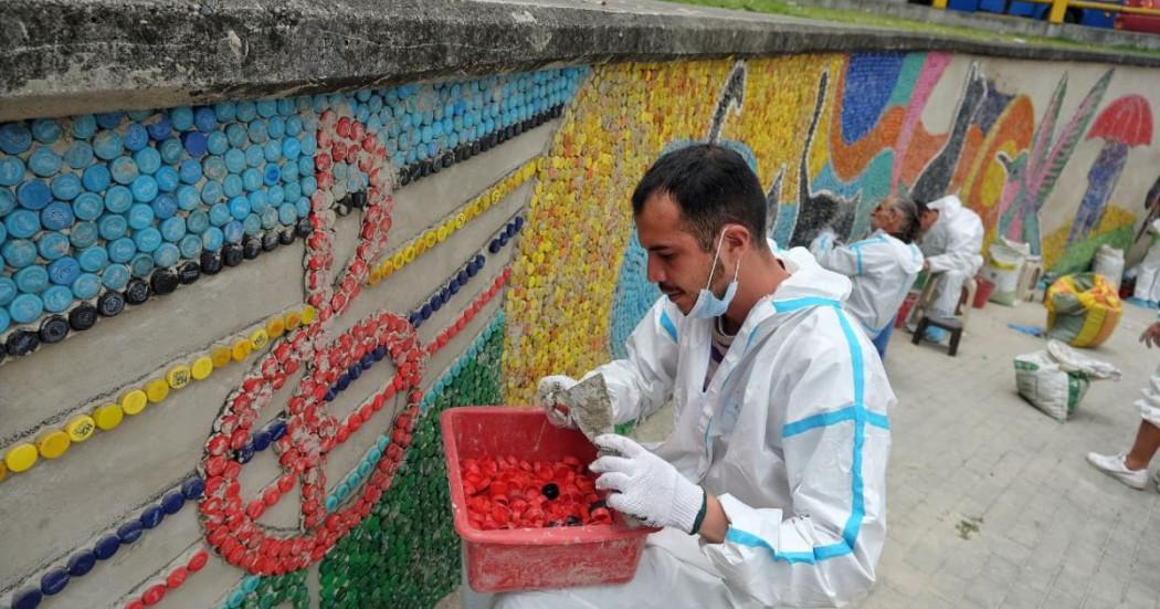 Imagen de ciudadanos en proceso de superación de vida en calle en la elaboración del mural de la estación Bicentenario de TransMilenio. 