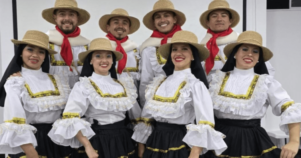 Imagen de varias mujeres jóvenes vestidas con trajes típicos de campesinas al fondo también está un hombre mayor con vestido de campesino