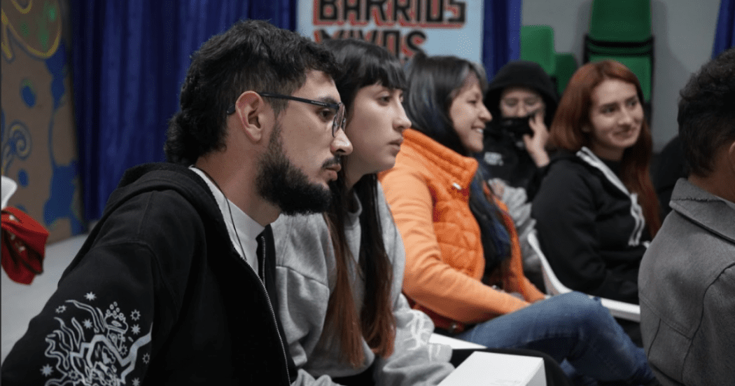 Imagen de varias personas, que sentadas prestan atención a alguien que esta de frente.