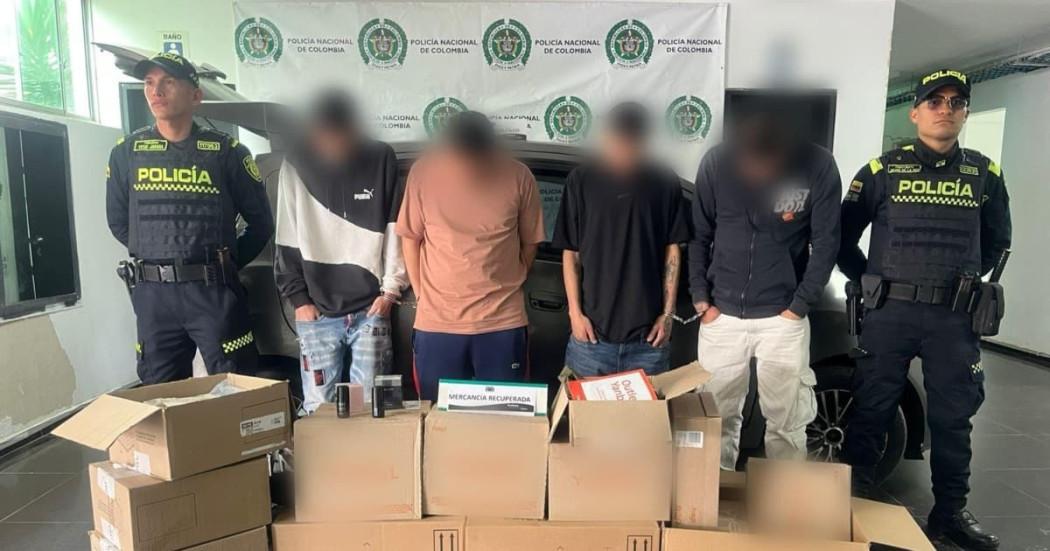 Foto de cuatro hombres capturados junto con mercancía recuperada
