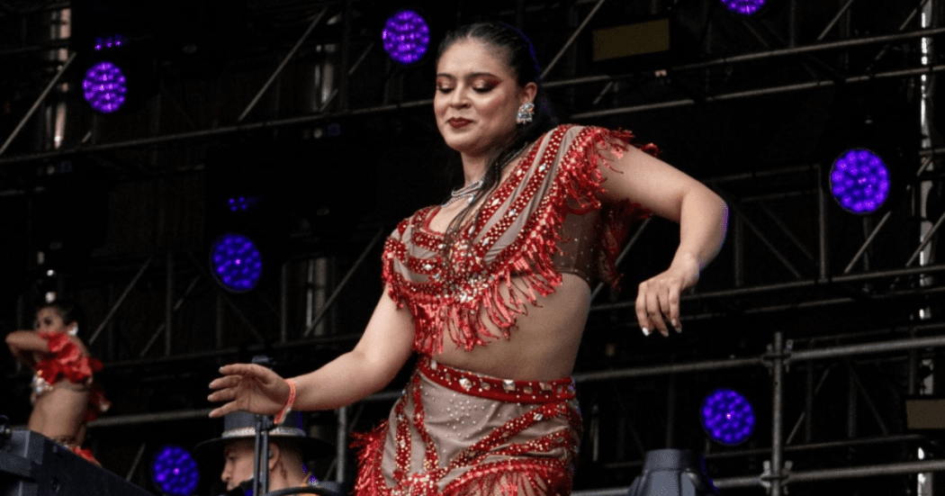 Imagen de mujer en esenario bailando salsa con la ropa caracteristica de estos bailarines