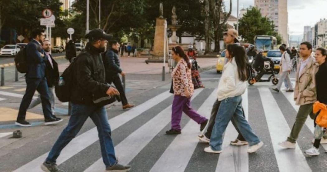 Foto de distintos peatones pasando por una vía de Bogotá
