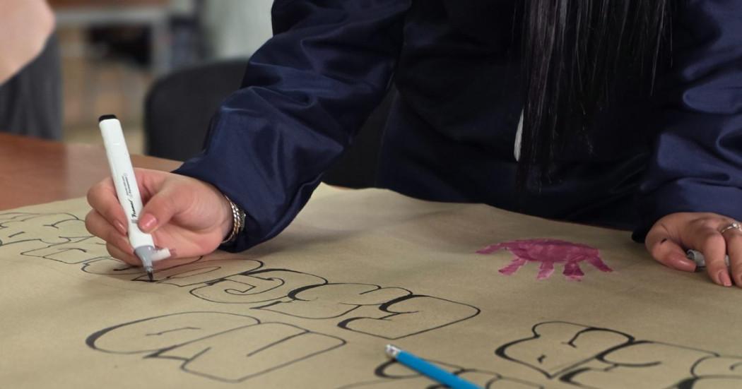 Imagen de un estudiante escribiendo una cartelera