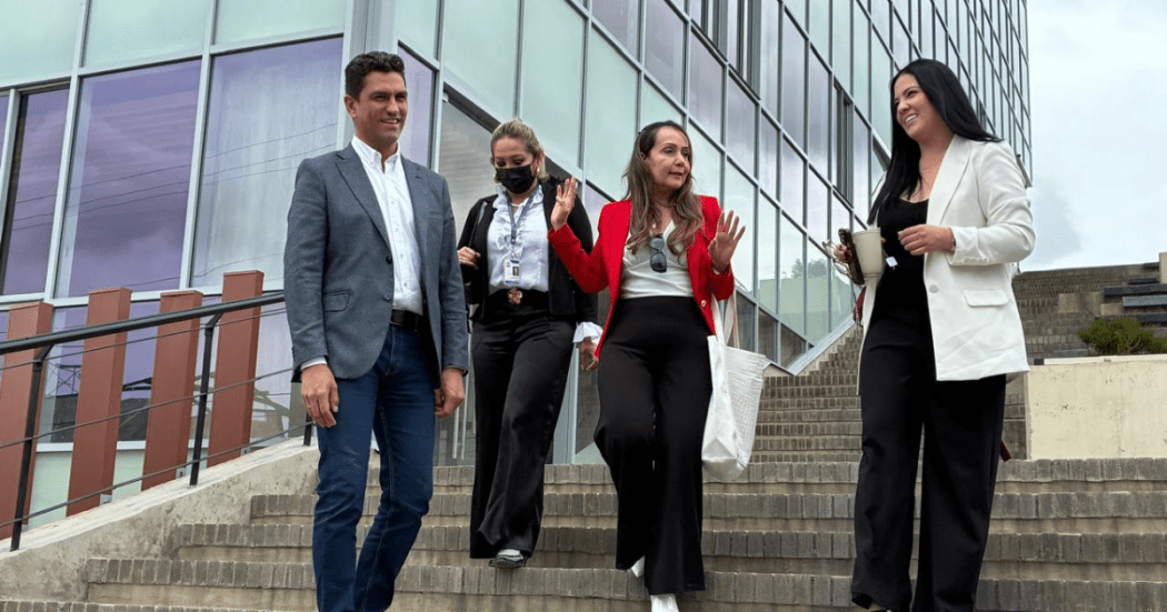 Foto de un grupo de cuatro personas que desciende unas escaleras frente a un edificio moderno mientras conversan y sonríen.
