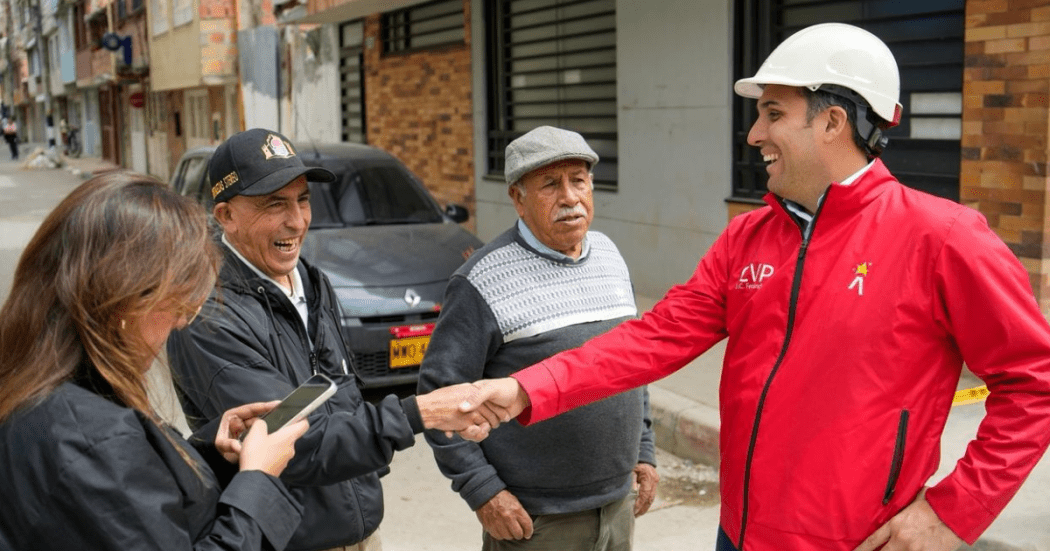 Un funcionario dialoga y estrecha la mano a vecinos del barrio mientras recorren las obras viales en la zona.