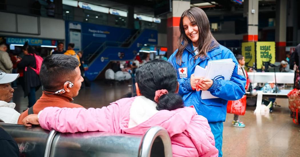 Una mujer de la Cruz Roja ofreciendo atención a una pareja migrante