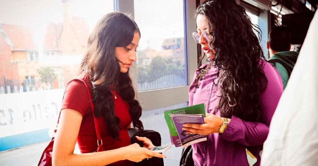 Una mujer que pertenece a la Secretaría de la Mujer le está mostrando un folleto a otra mujer
