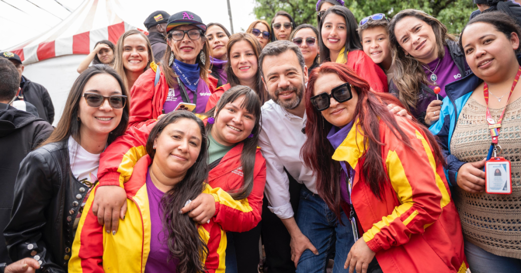 Foto de un grupo de mujeres y un funcionario sonríen juntos durante una jornada comunitaria.