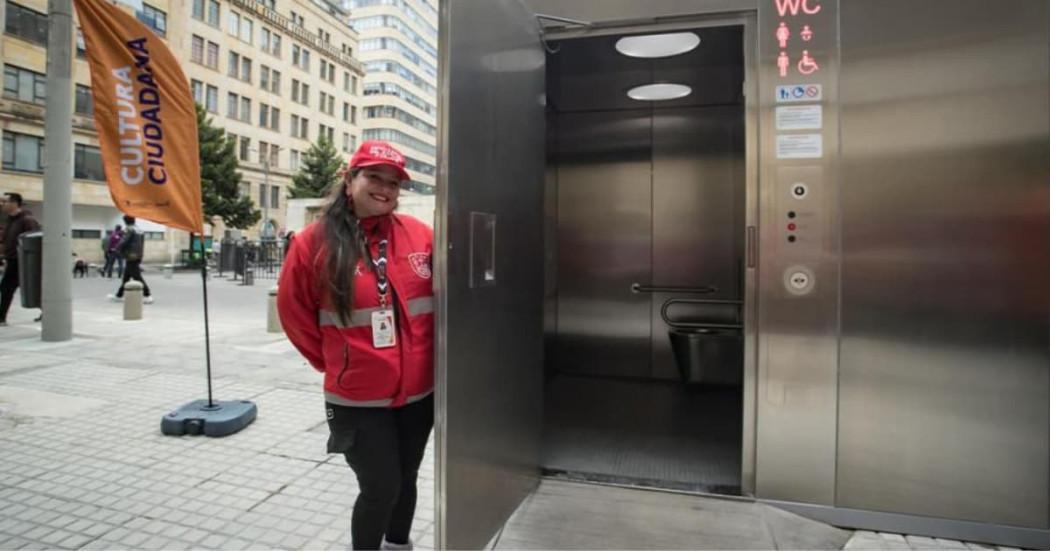 Señora posando con el baño público en Bogotá