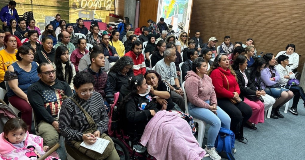 Foto de una comunidad diversa que se reúne en un espacio participativo, mientras familias y cuidadores escuchan y dialogan en torno a la discapacidad.
