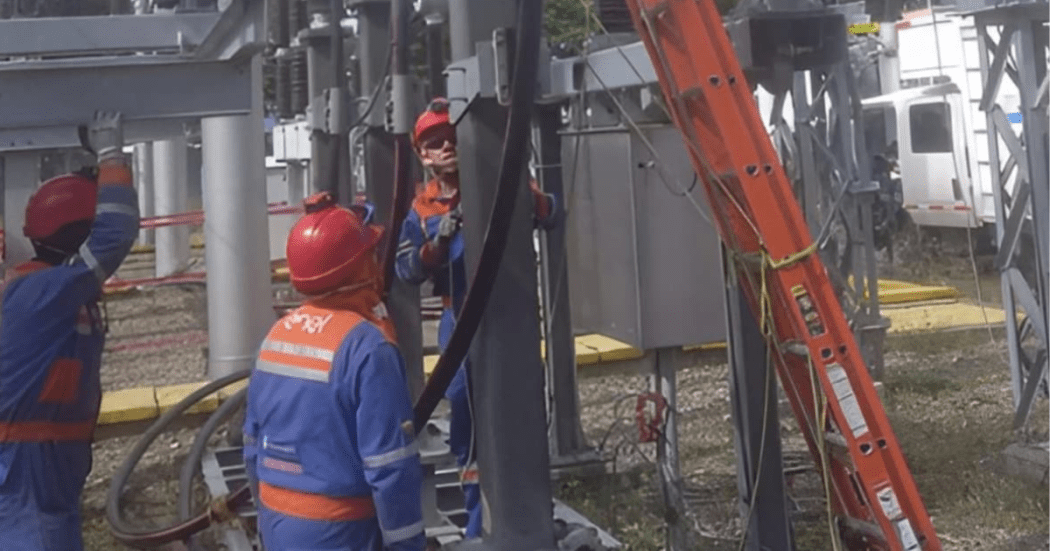 Imagen de tecnicos de Enel que revisan los cables de energía de un poste.