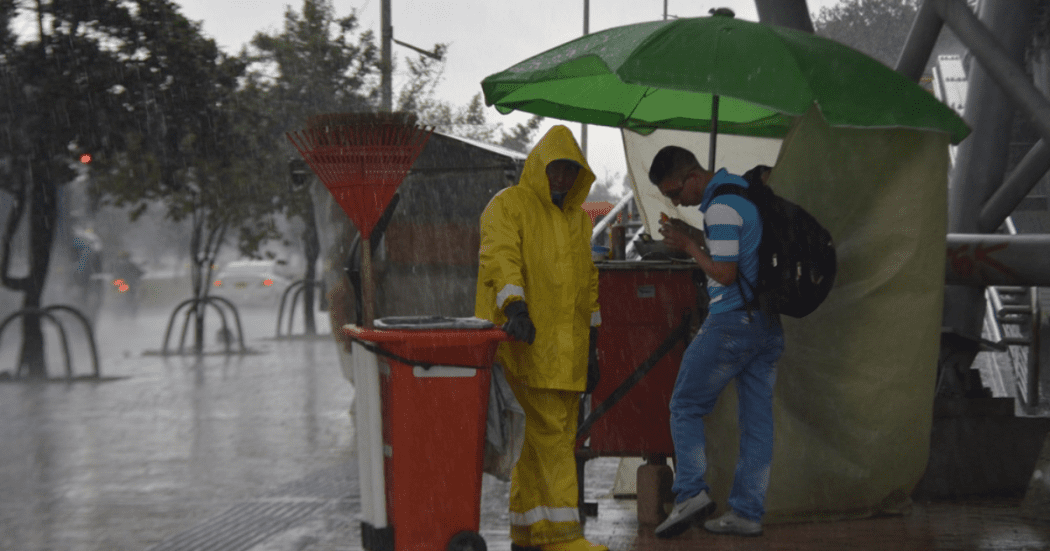 Imagen de dos personas escampando de la lluvia en Bogotá