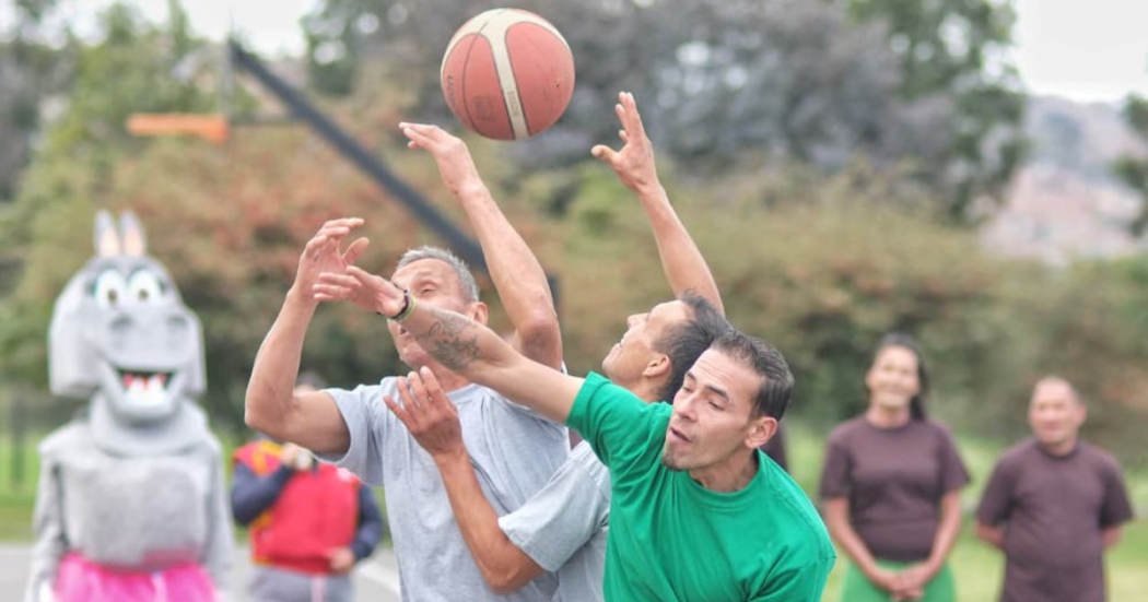 Imagen de tres personas disputando el balón de baloncesto