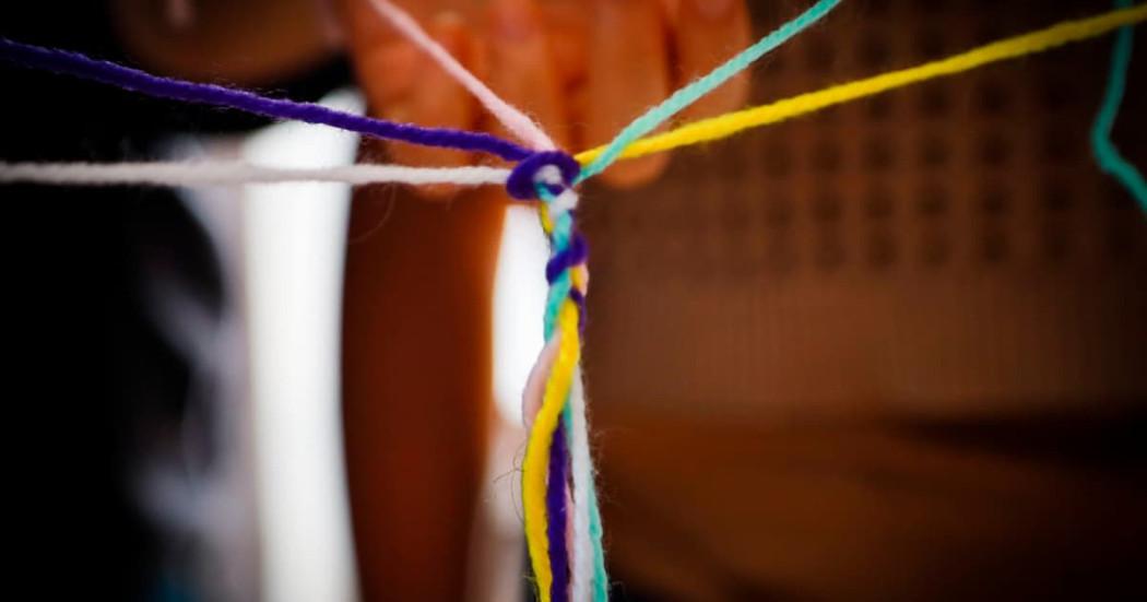 En la foto unas personas tejiendo redes de manera simbólica