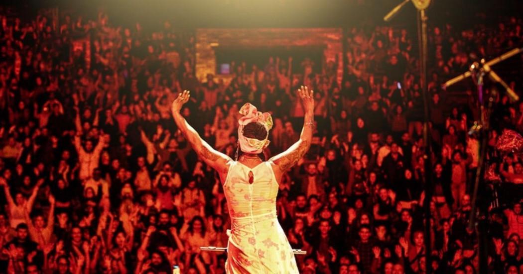 Imagen de una mujer de espaldas al frente de una multitud de personas