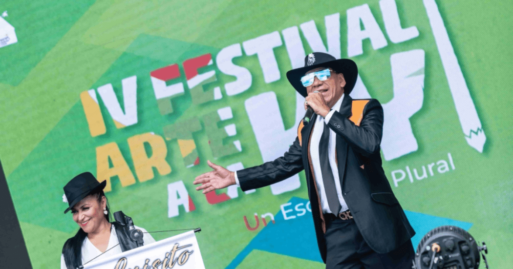 Imagen de cantante en tarima, de fondo se ve información del festival