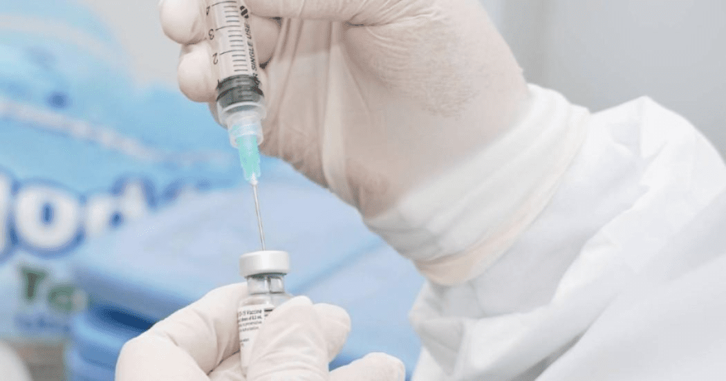 Imagen de unas manos que usan guantes y están preparando una vacuna