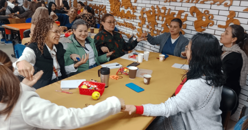 Imagen de varias personas tomándose de la mano alrededor de una mesa