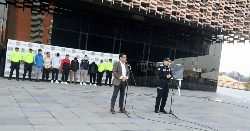 Imagen de la rueda de prensa en la que se ve al secretario de seguridad y detrás de él a los capturados