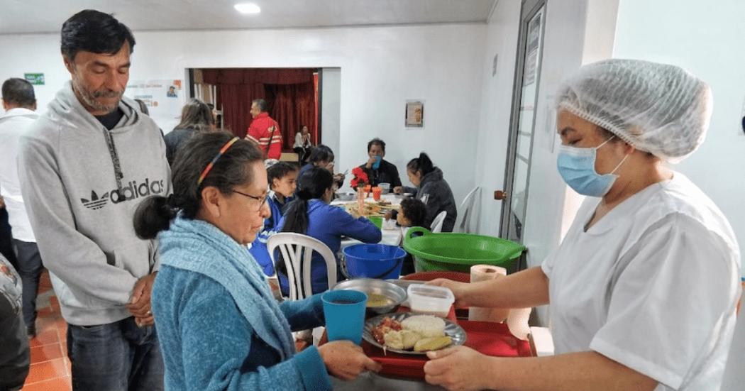 Imagen de una mujer recibiendo la bandeja del almuerzo