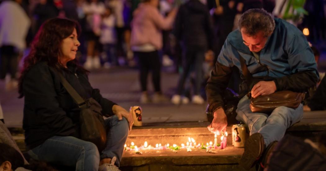 Foto que muestra dos personas sentadas en el piso prendiendo velas