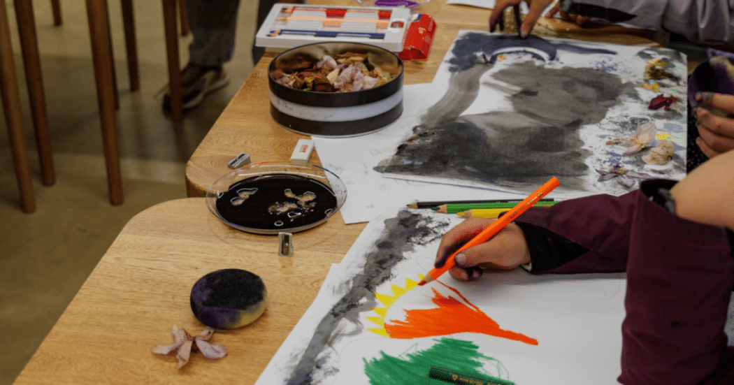Imagen de varias personas sentadas en una mesa realizando actividades de artes plásticas.