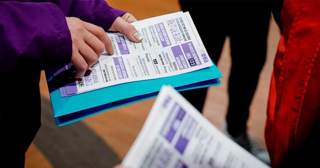 En la foto una seora mostrando un folleto con información sobre lo servicios de la Secretaría de la Mujer