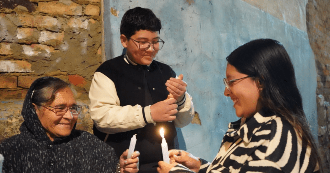 Foto de 3 personas prendiendo velas en Bogotá 