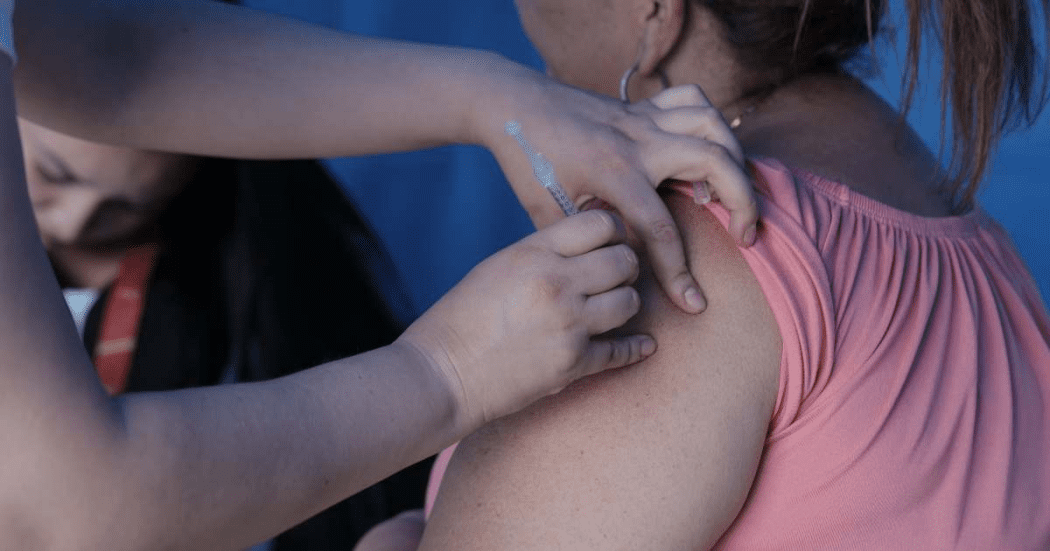 Imagen de unas manos que colocan una vacuna en un brazo