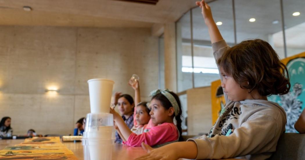 Foto que muestra niños y niñas sentados en una sala 