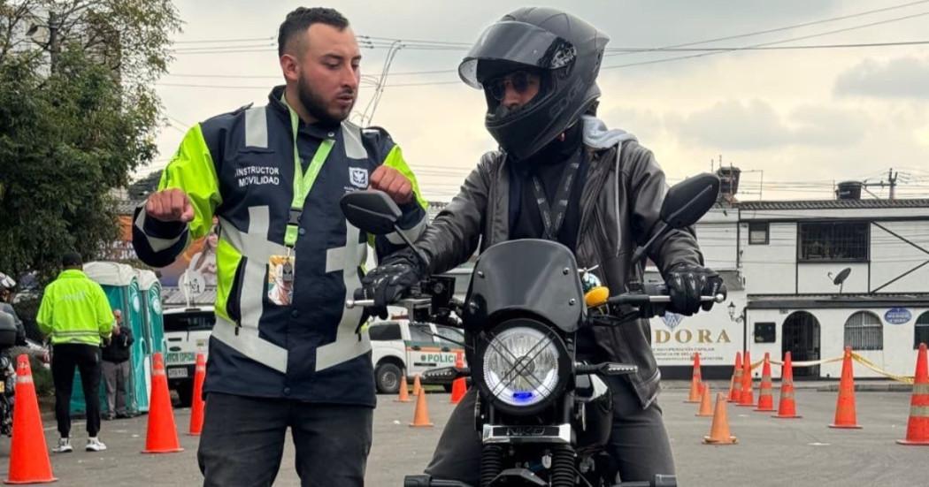 Foto de un hombre en una moto junto a un funcionario de Movilidad. 