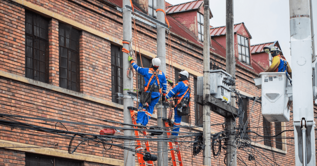 Imagen de técnicos de Enel colgados en postes de luz
