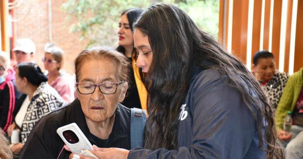 Funcionaria y mujer adulto mayor revisando información en el celular