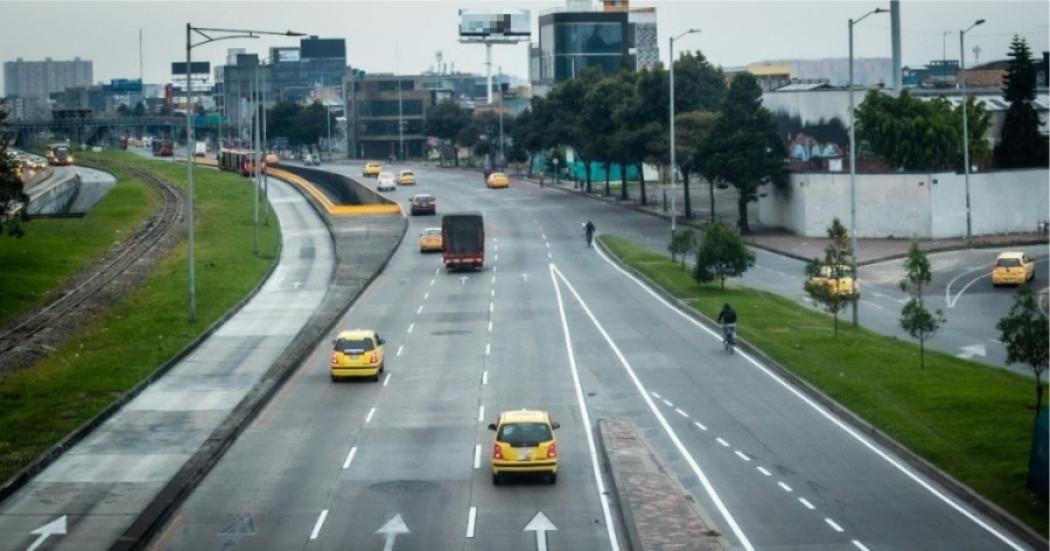 Imagen panoramica de una vida principal de Bogotá en la que se observan las demarcaciones de tránsito y en la que circulan buses, vehíclos particulares y taxis.