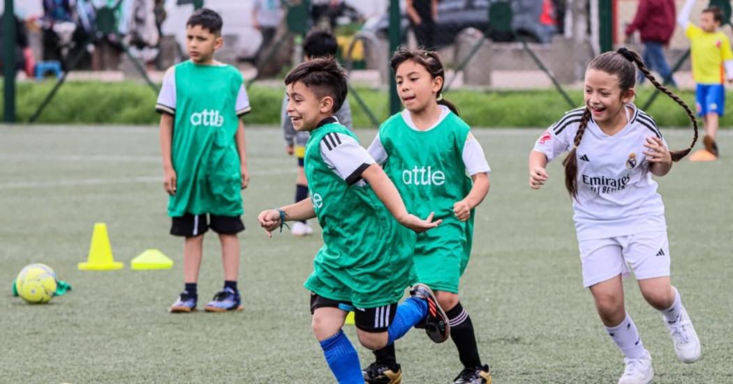 Foto de niños y niñas realizando prácticas deportivas en una cancha de fútbol.