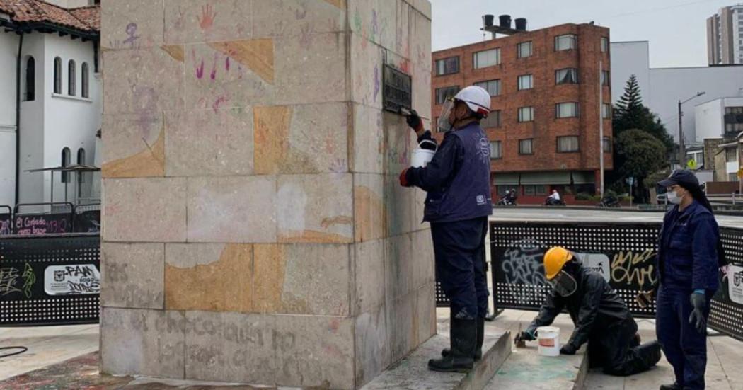 Foto que muestra un monumento de la ciudad y tres personas limpiandolo