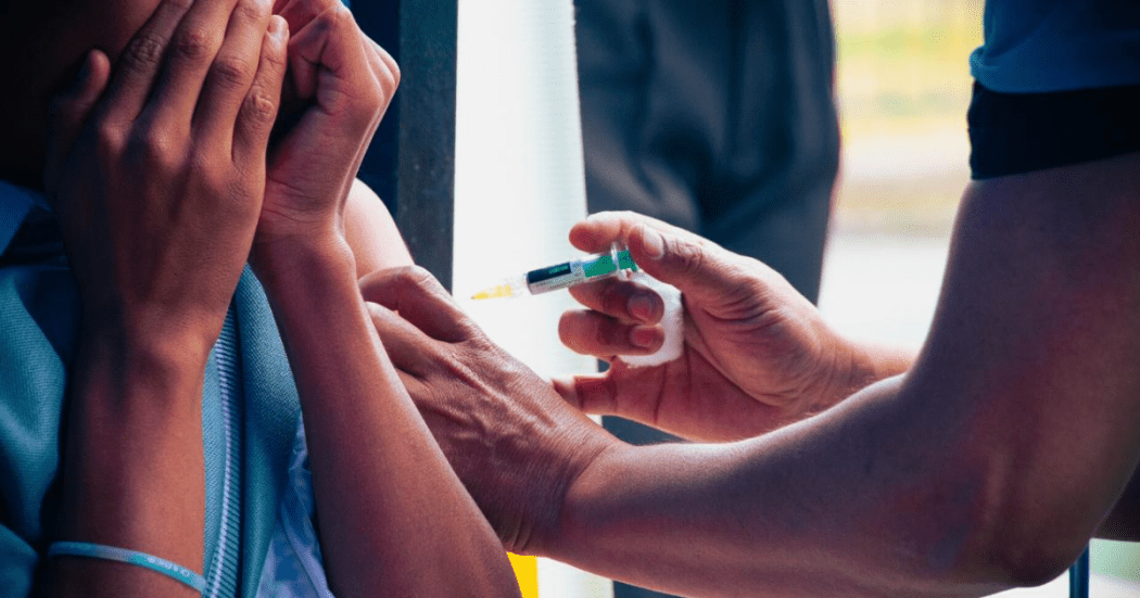 Foto de una enfermera colocando una vacuna en el hombro de una persona