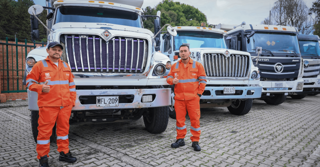 Imagen de dos operarios de aseo junto a camiones recolectores