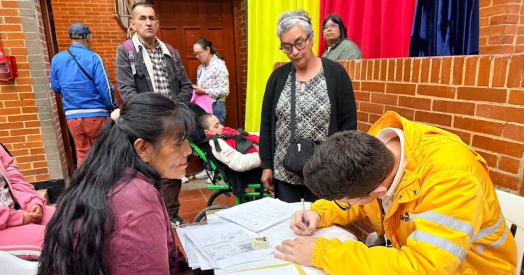 Imagen de un funcionario de Integración Social atendiendo a una mujer y llenando un formulario