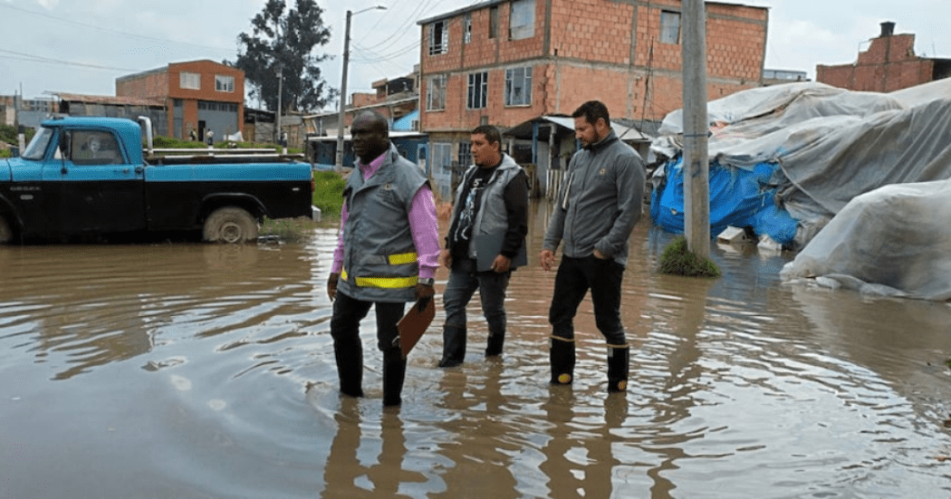 Imagen de tres personas caminando en un charco