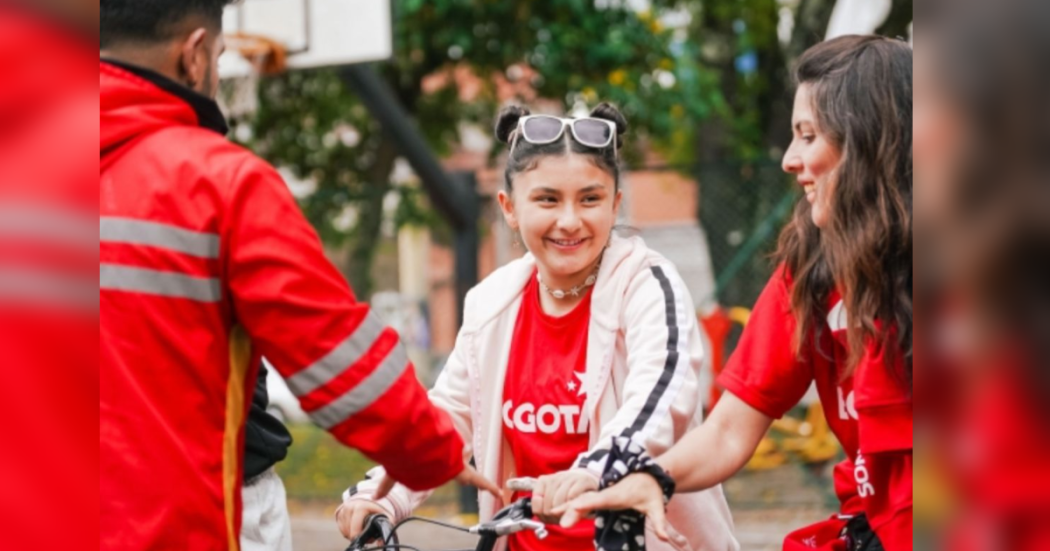Imagen de niña en bicicleta recibiendo instrucción de los profesores